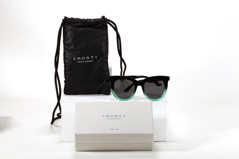 Este set de accesorios para gafas de la marca Crosty incluye una bolsa negra, un estuche blanco y unas gafas de sol de diseño elegante.