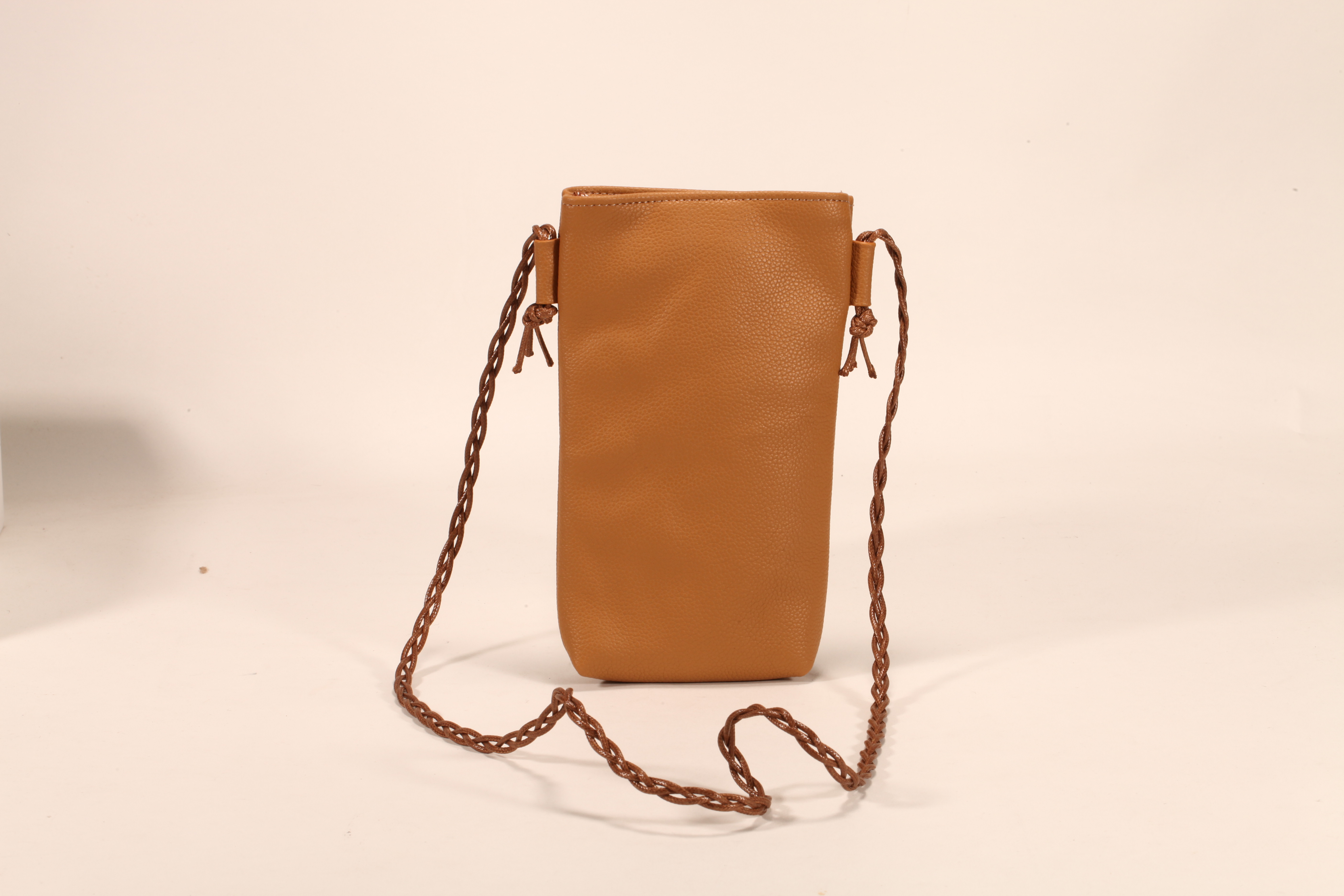 Este es un bolso de cuero marrón. Tiene un cordón y puede almacenar móviles y lentes de sol. Es práctico y elegante.