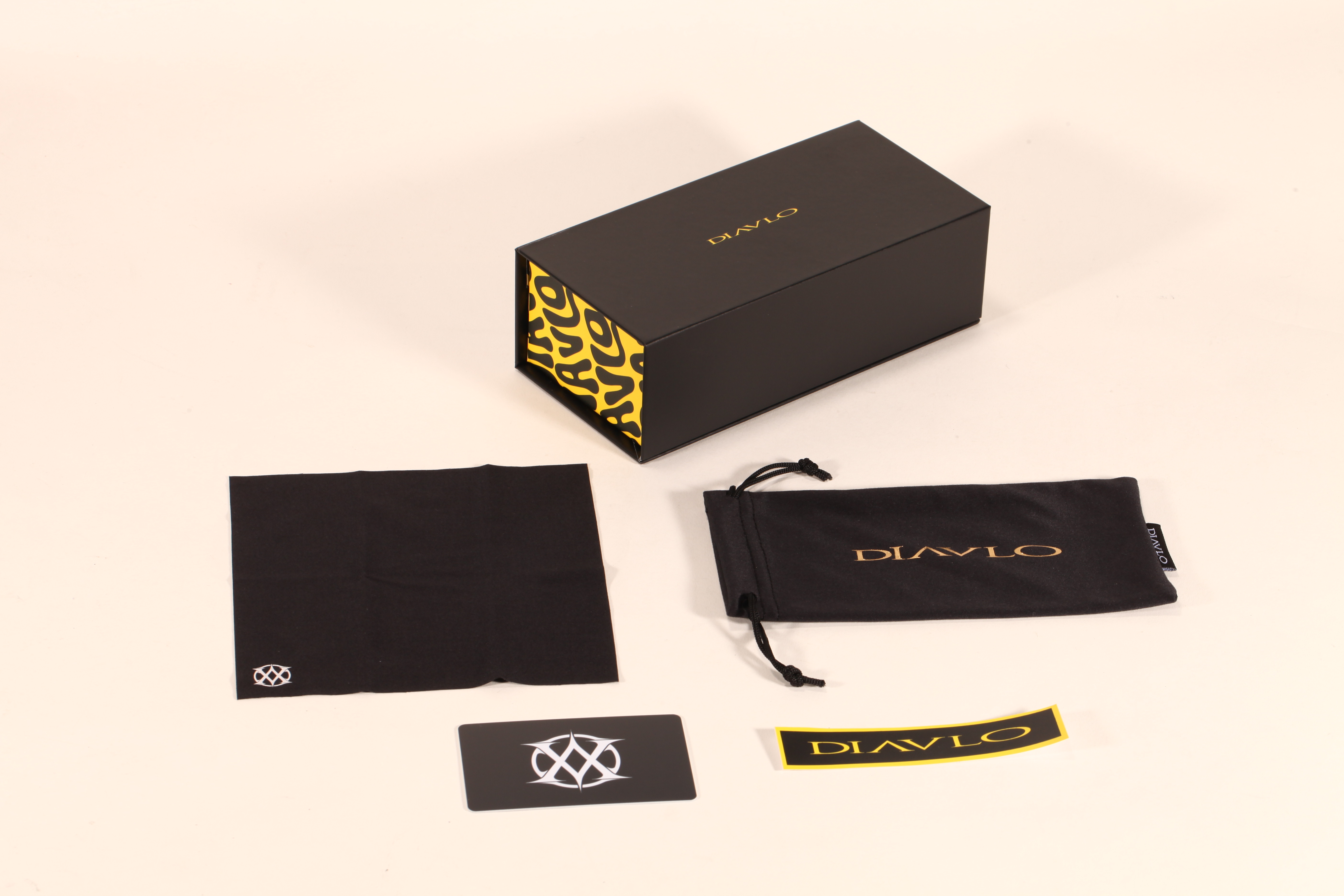 This eyewear case set includes a black box with yellow pattern, a pouch, cloth and tags.