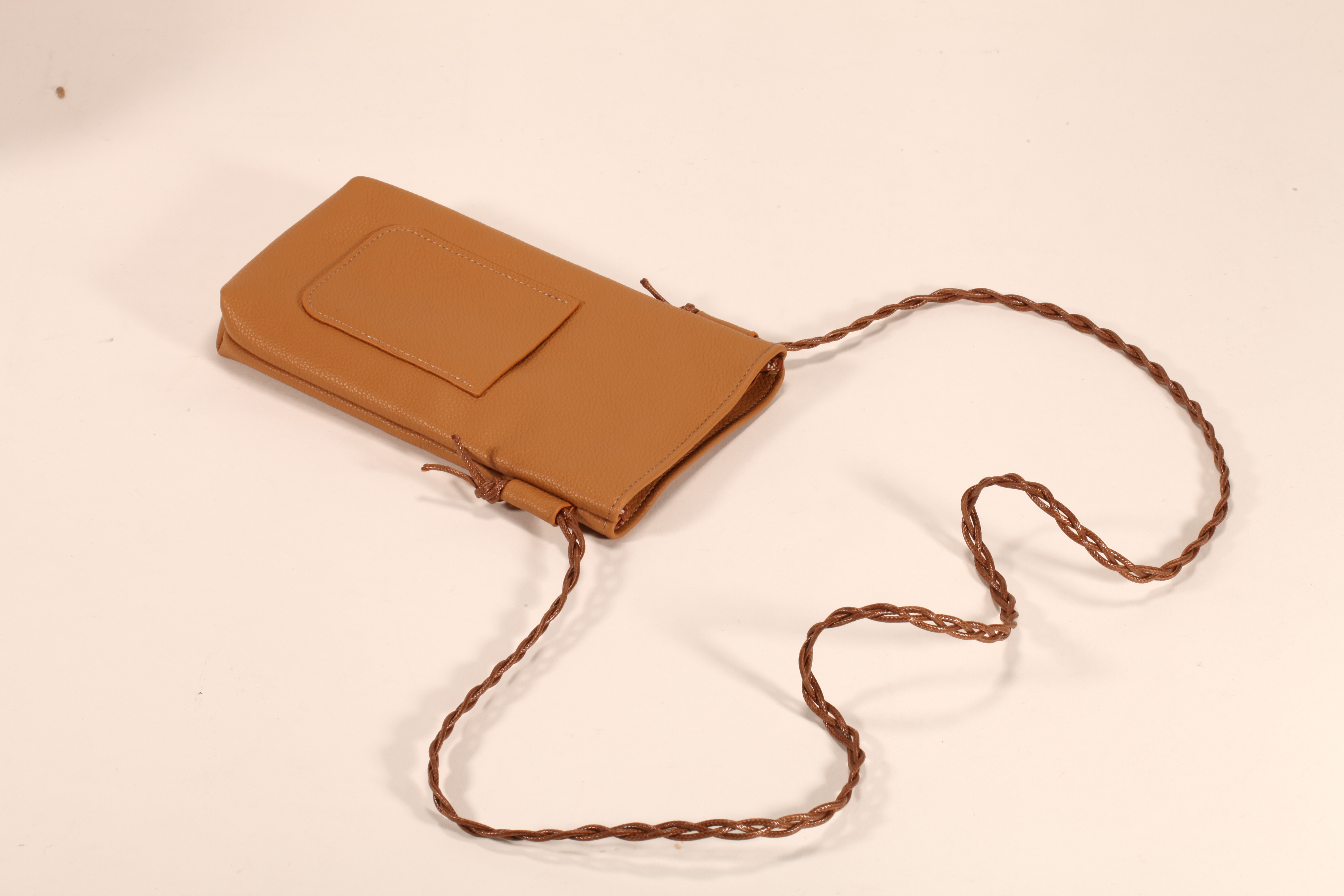 Este es un bolso de cuero marrón. Tiene un cordón y puede almacenar móviles y lentes de sol. Es práctico y elegante.