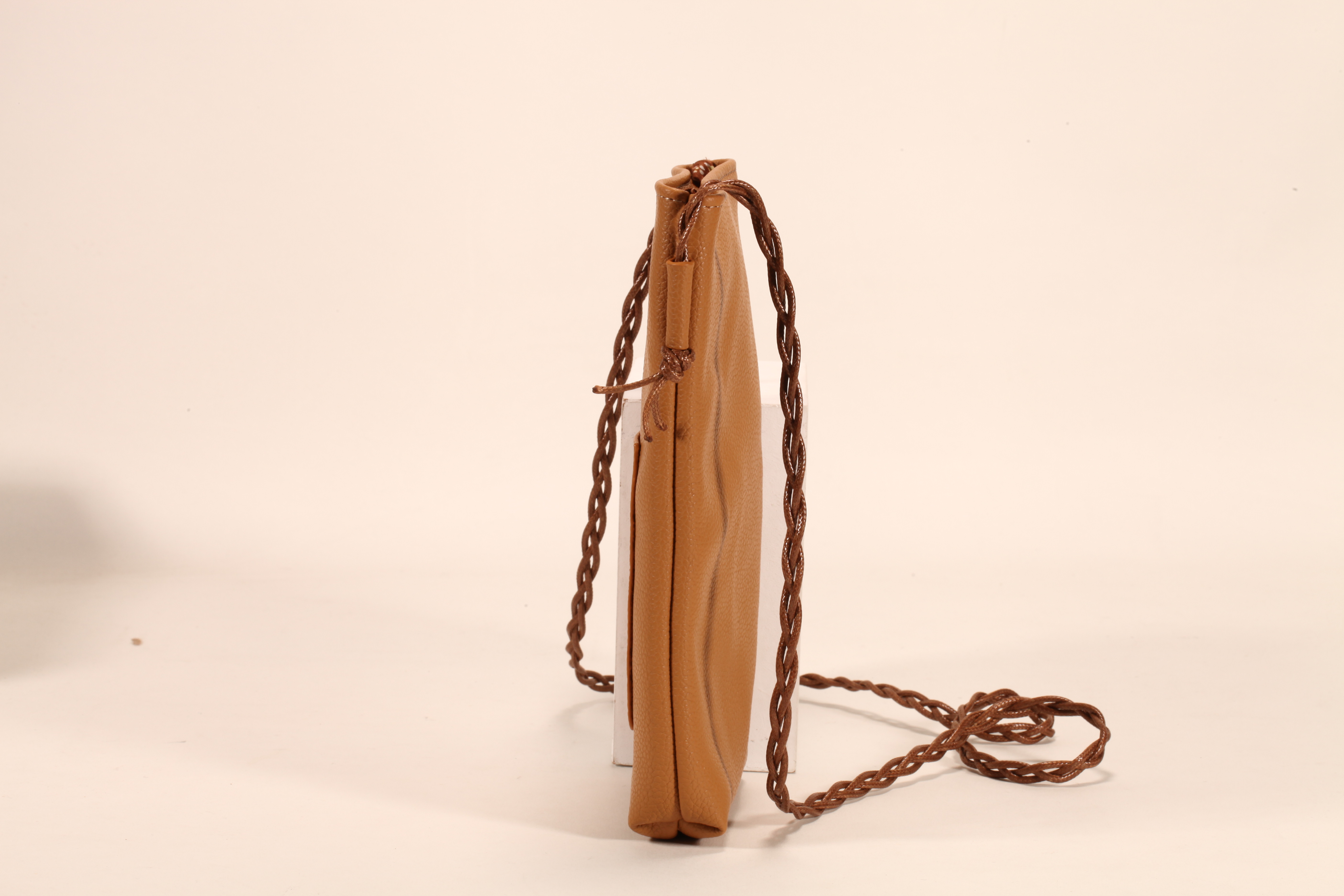 Este es un bolso de cuero marrón. Tiene un cordón y puede almacenar móviles y lentes de sol. Es práctico y elegante.