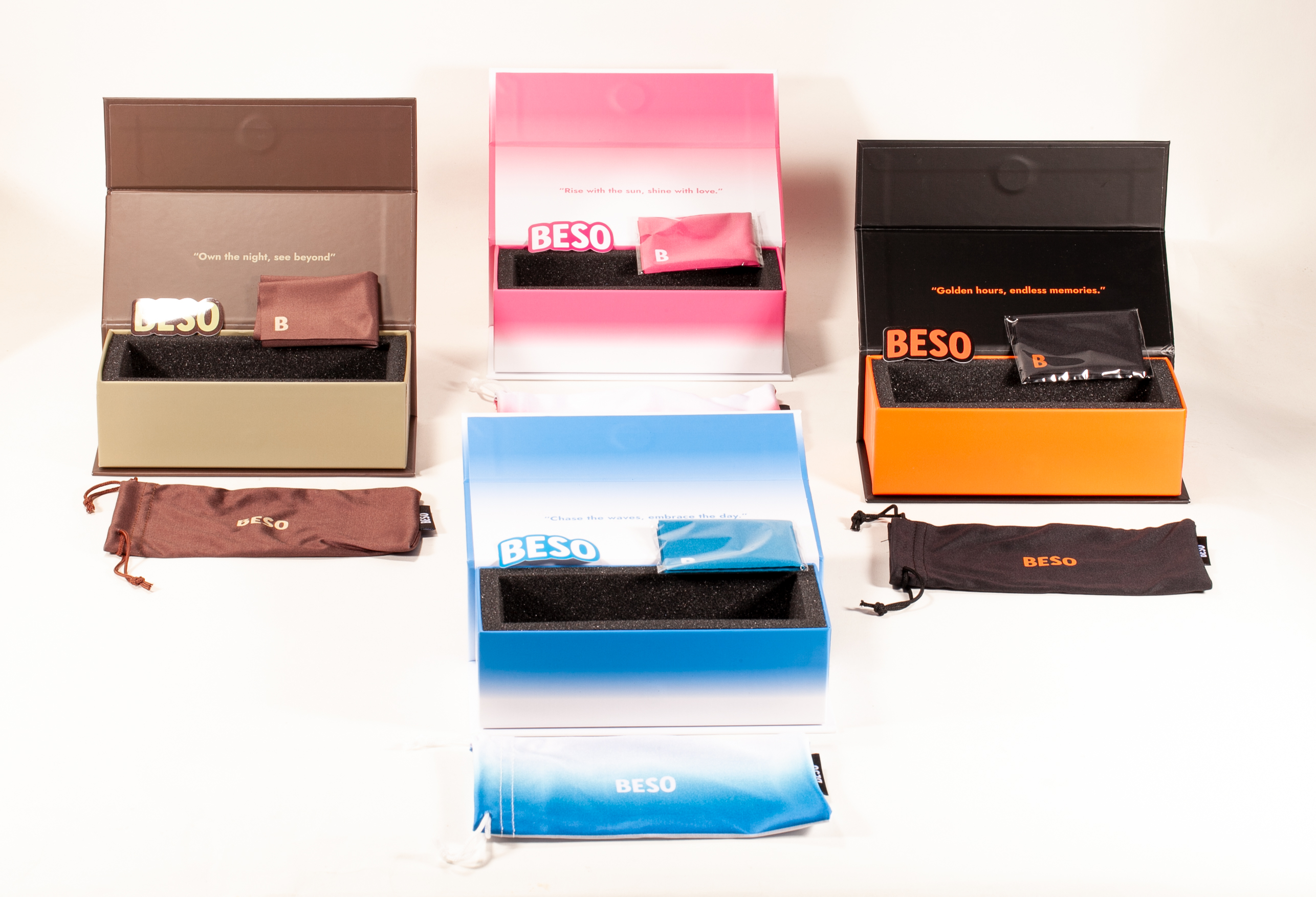 This image displays four rectangular BESO eyewear boxes in varied colors: pink, brown, black, and blue. They feature bold logos in contrasting shades, with some showcasing gradient designs. The clean,