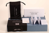 Here is a 50-word English description for the eyewear set shown in the image: This eyewear set features a white paper box and matching soft pouch, measuring 17×4×7 cm. Branded with Christian Wijnants
