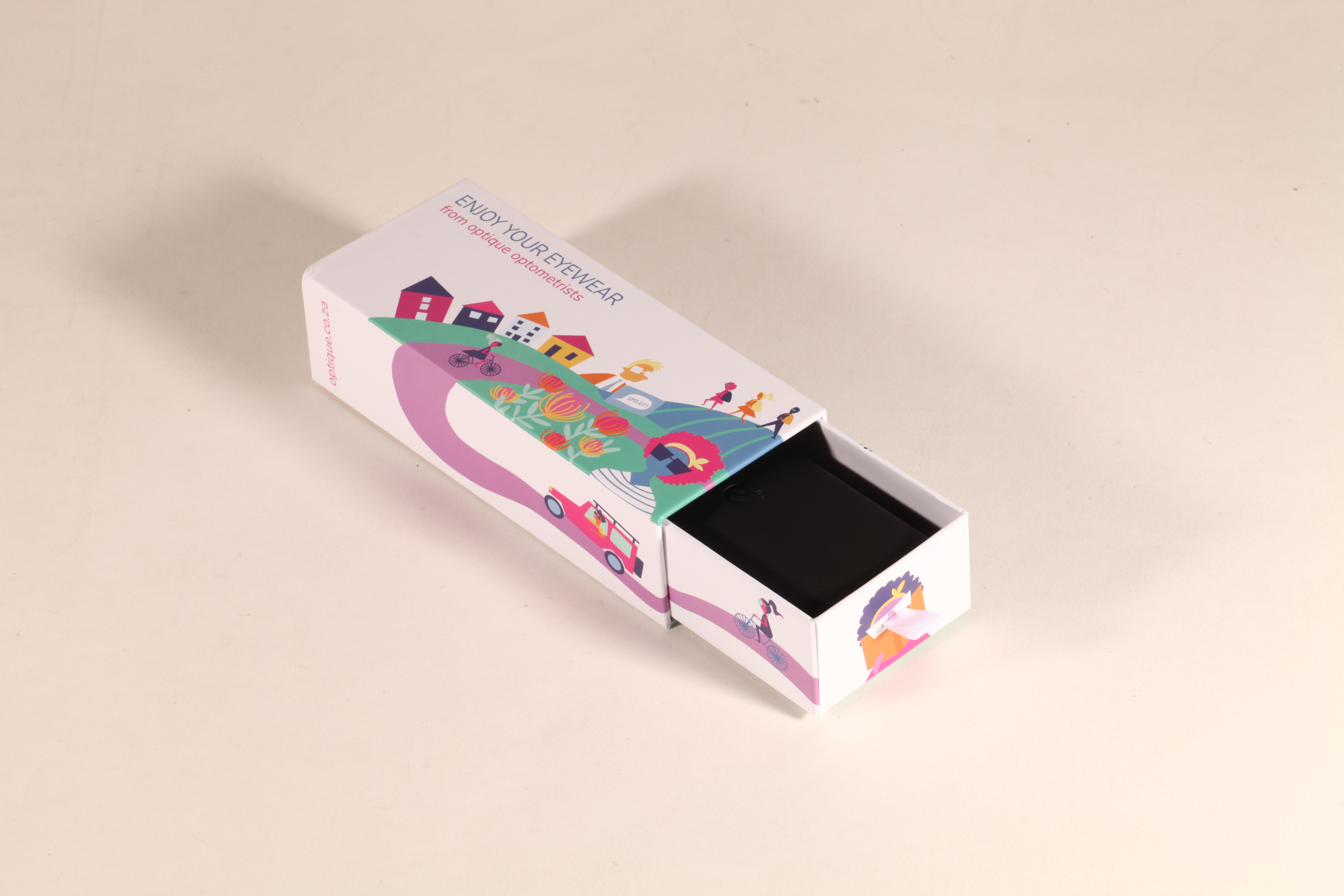 Here's a 50-word English description for the eyewear set shown in the image: This Optique eyewear set includes a white paper box and a soft matching pouch. Featuring the tagline "ENJOY YOUR EYEWEAR" 