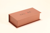 This Valoré eyewear set features a pink box, a tan semi-circular leather case (with gold snap), and a small square card. It exhibits elegant minimalist design, premium texture, and consistent branding