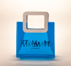 Three translucent bags in green, pink, and blue feature white square handles. The front displays the black text "MARMOTT EYEWEAR".